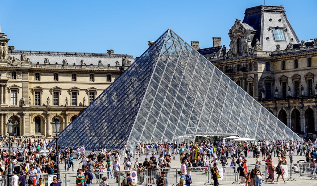 Gente contemplando el Louvre, una de las piramides de cristal mas importantes del mundo.